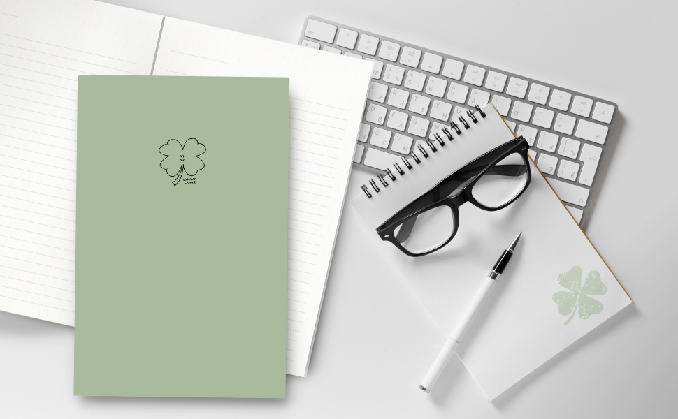 lucky cunt notebook on desk next to a keyboard, glasses, pen and notepad