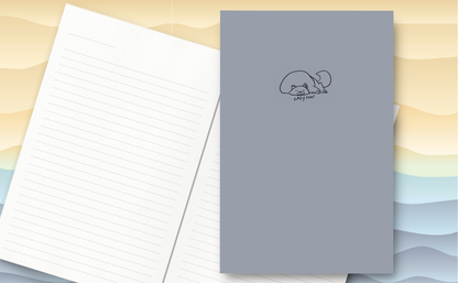Cute drawing of a cat sleeping with the words 'lazy cunt' on a soft matte cover. Inside lined pages.